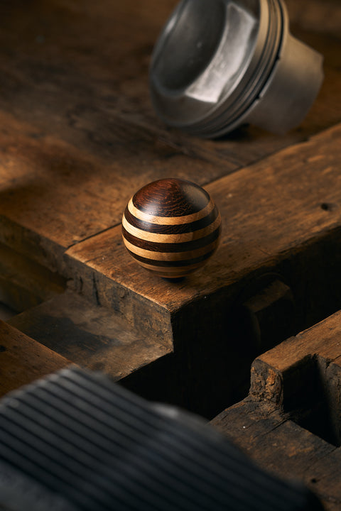 Wooden ball with striped pattern on a rustic wooden surface