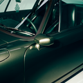 Close-up of a green car's side mirror and door handle on a white background