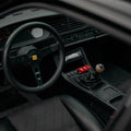 Interior view of a Porsche 944 with a gear shift knob made of layered wood and a MOMO steering wheel